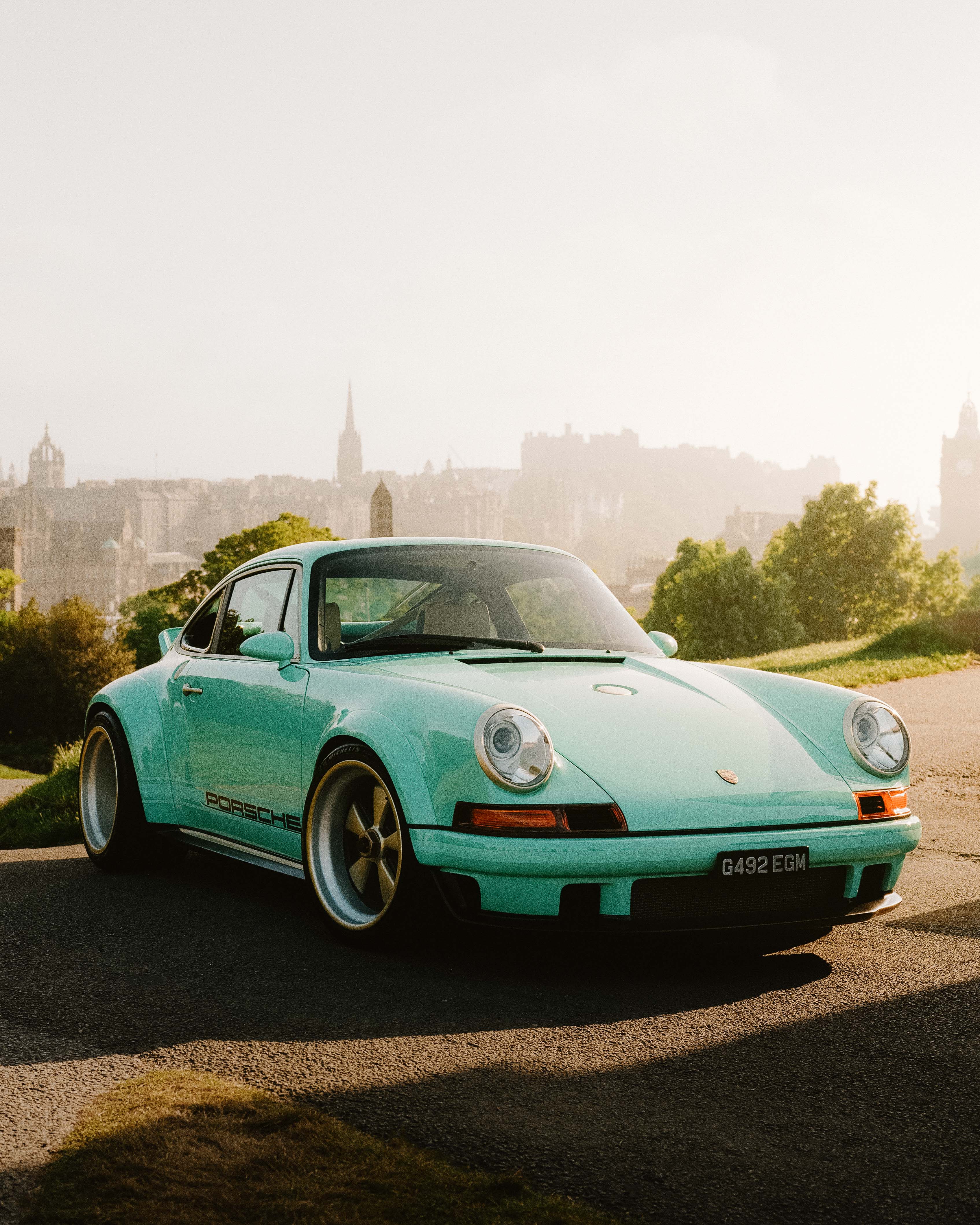 A teal Porsche againt a back drop of Edinburgh